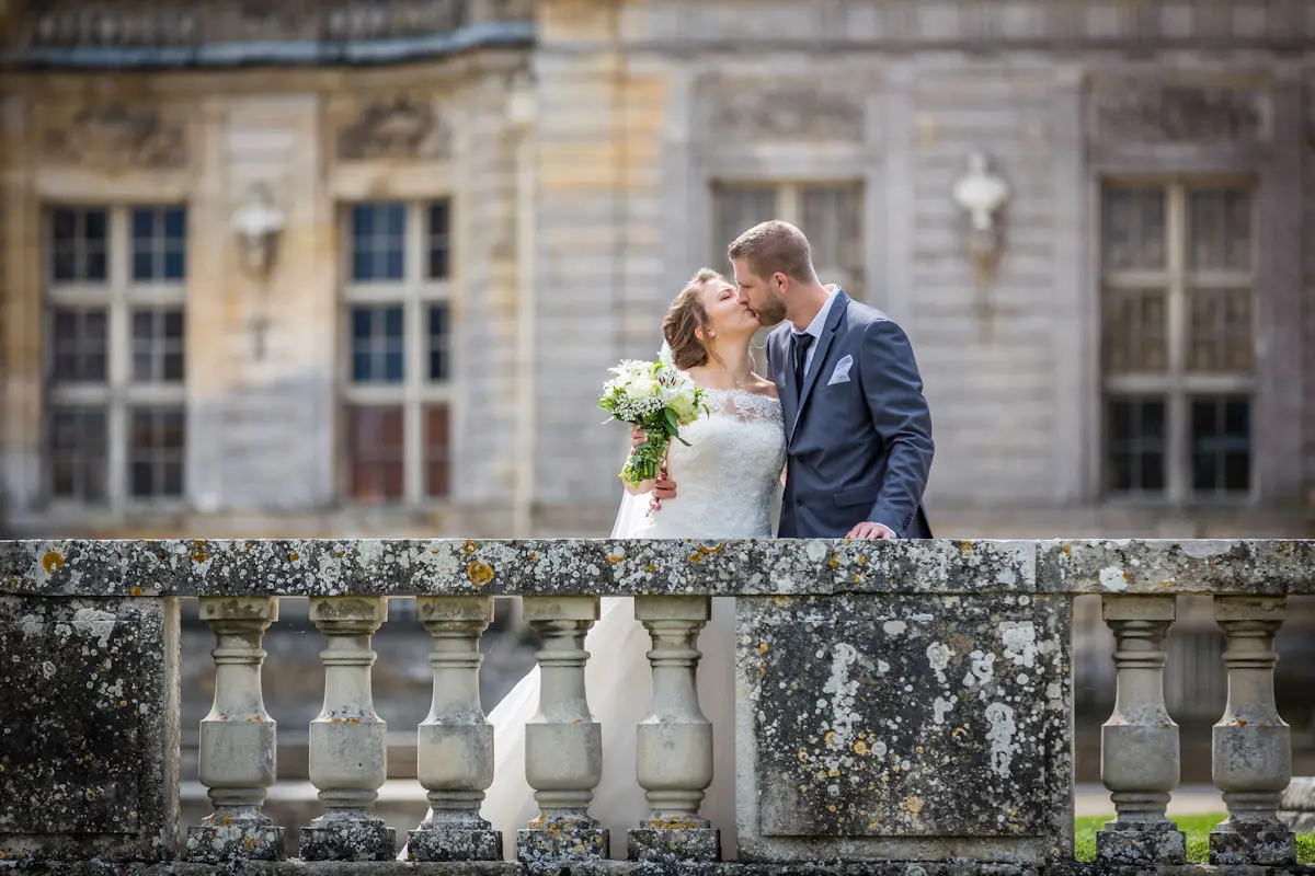 Baiser des mariés devant un château majestueux